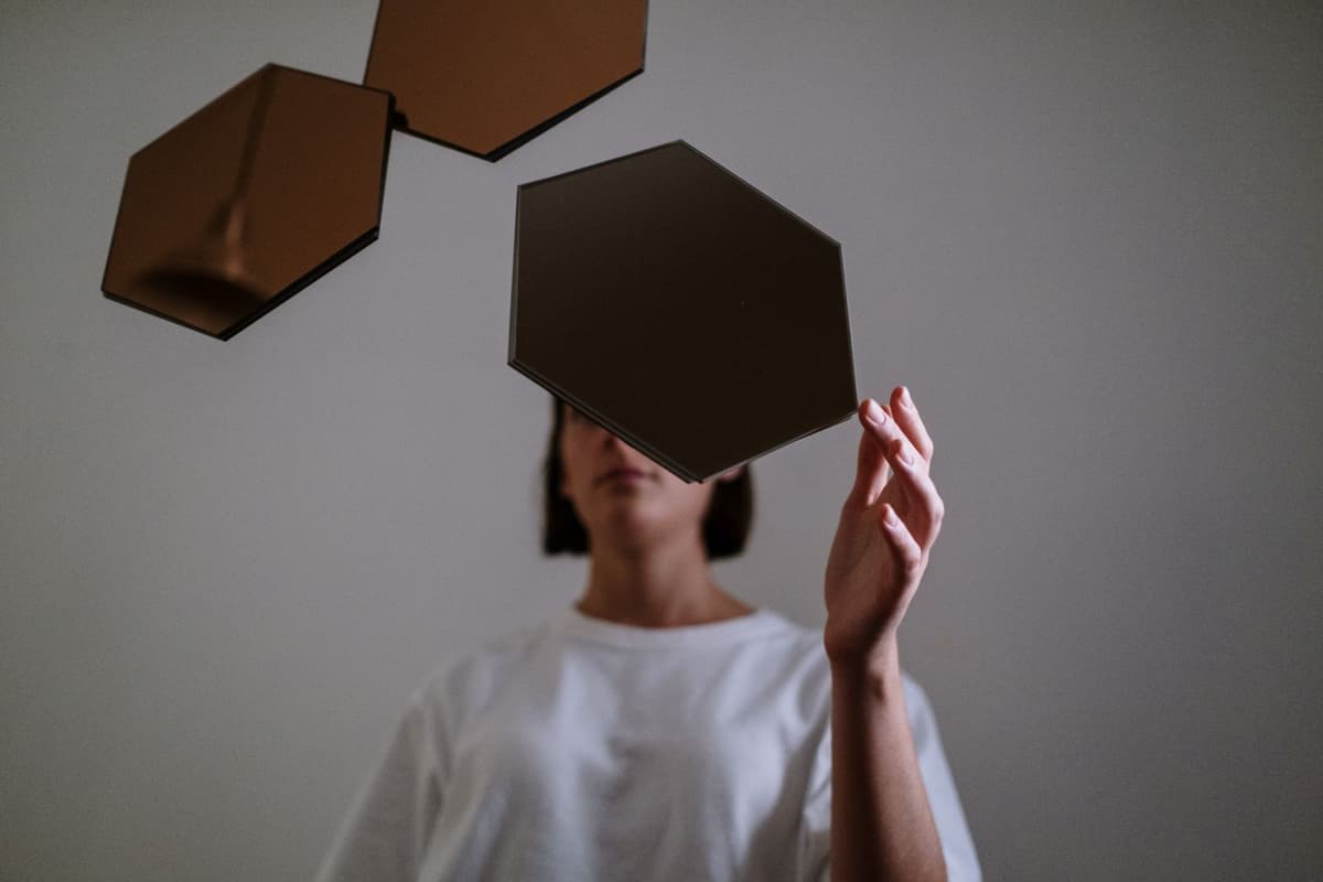 A person arranging mirrored shapes as a visual metaphor for observing thoughts.