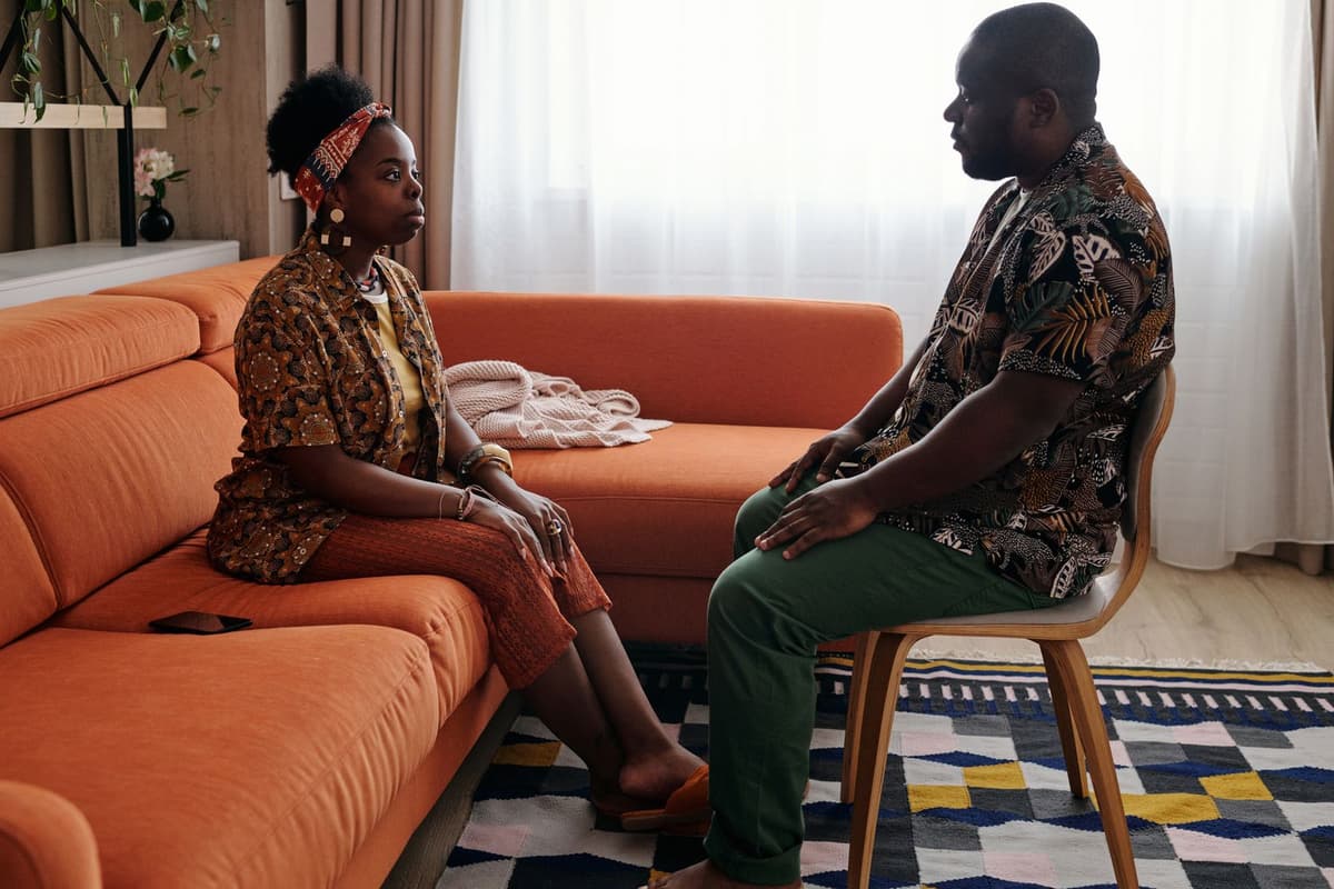 Two people seated on a sofa during a focused conversation.