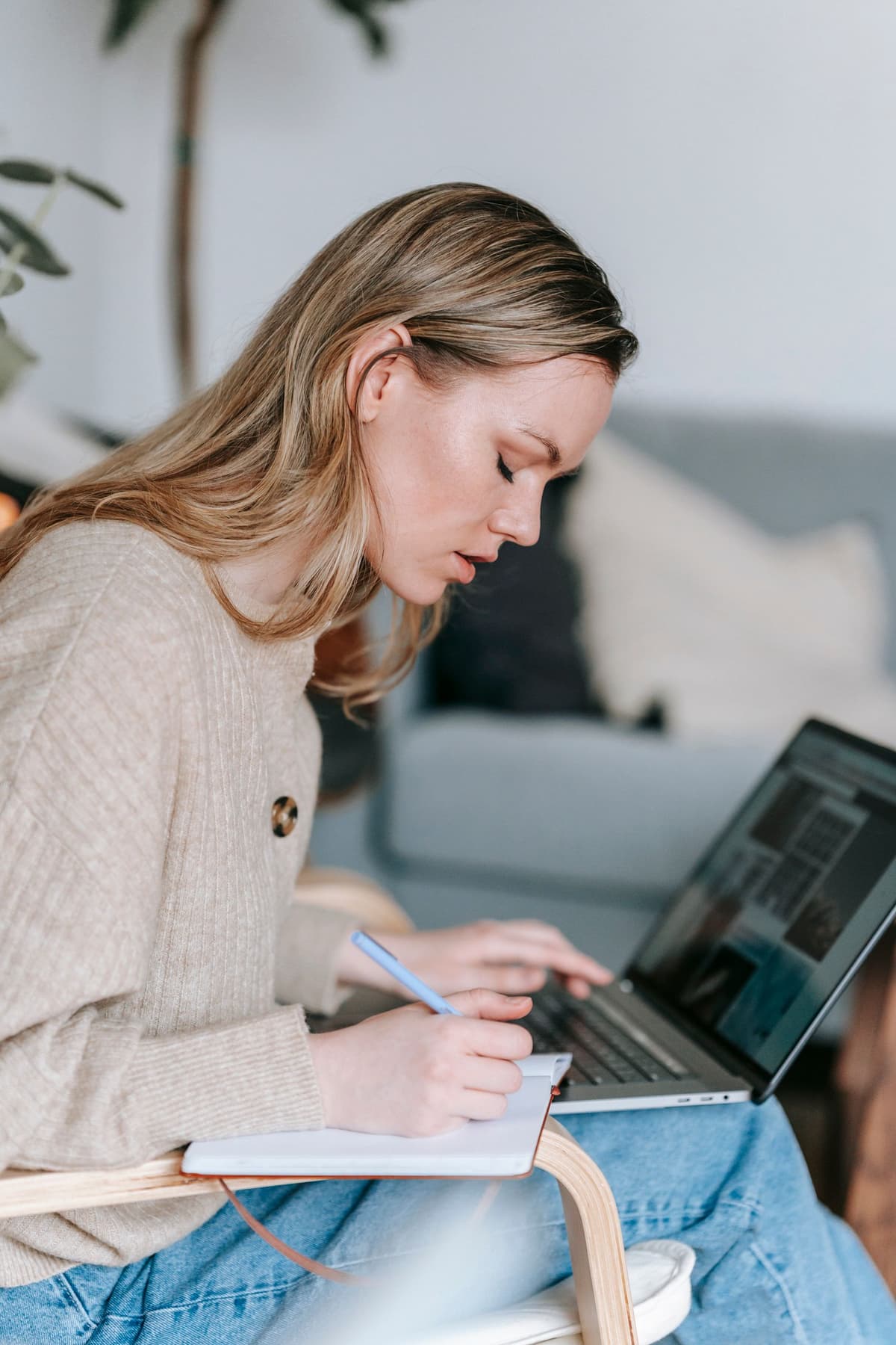 A person writing in a planner while using a laptop.