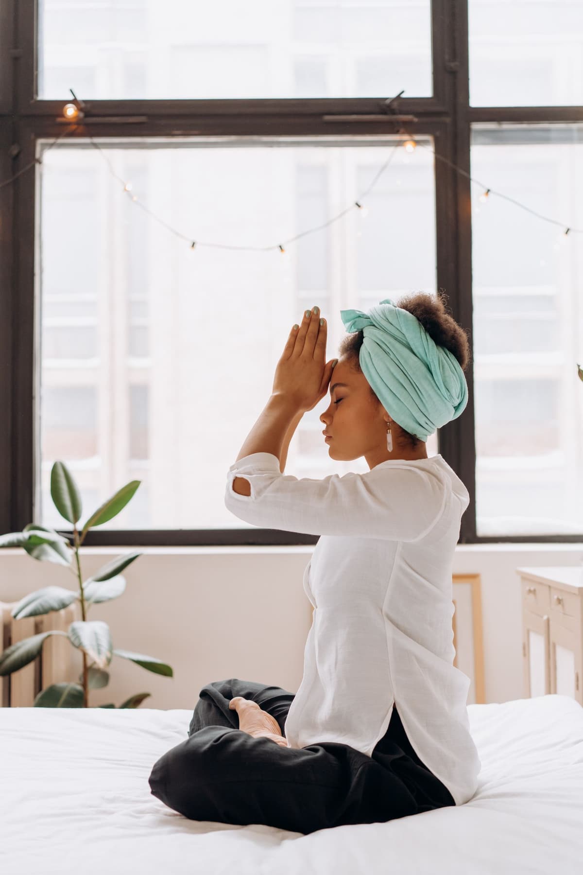 A person practicing quiet mindfulness while seated beside a bright window.