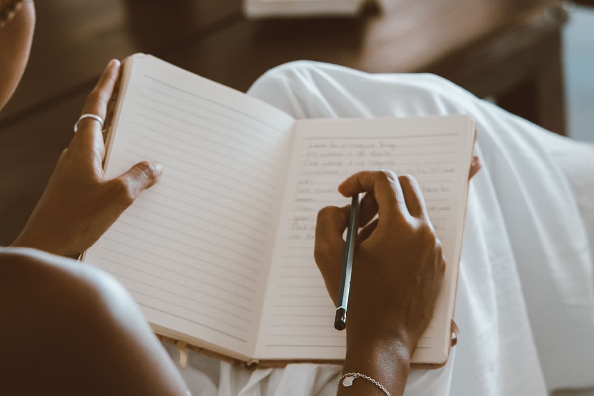 Close-up of hands writing in a notebook, matching the idea of a DBT diary card practice.