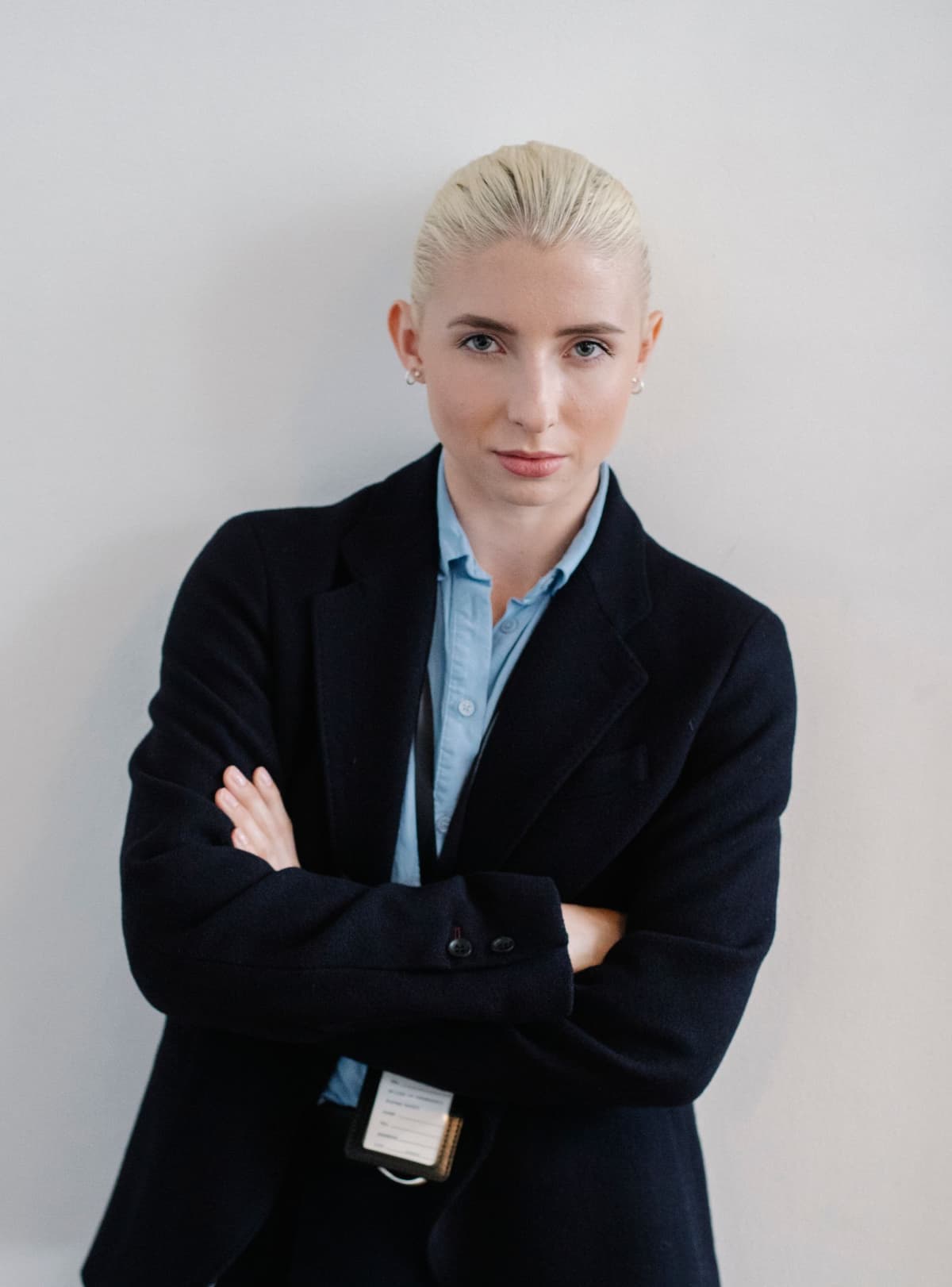 A self-assured professional standing calmly with her arms crossed.