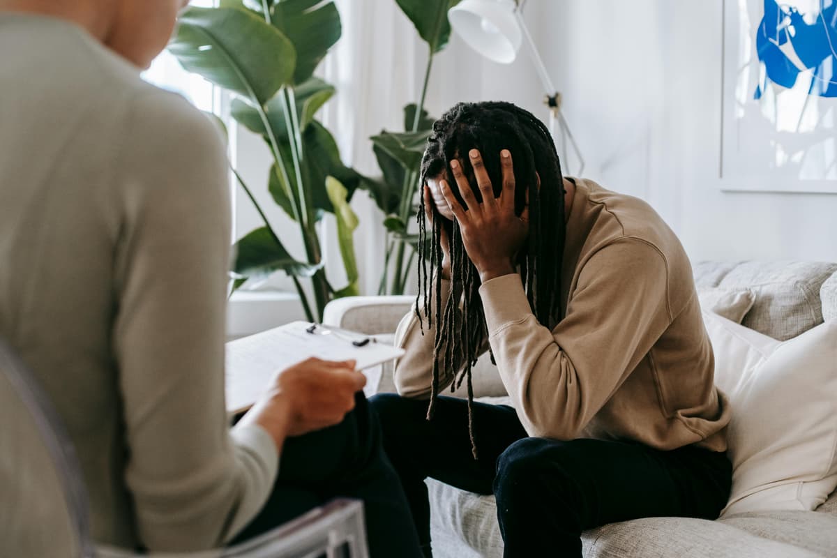 A distressed person seated on a couch during a counseling session.