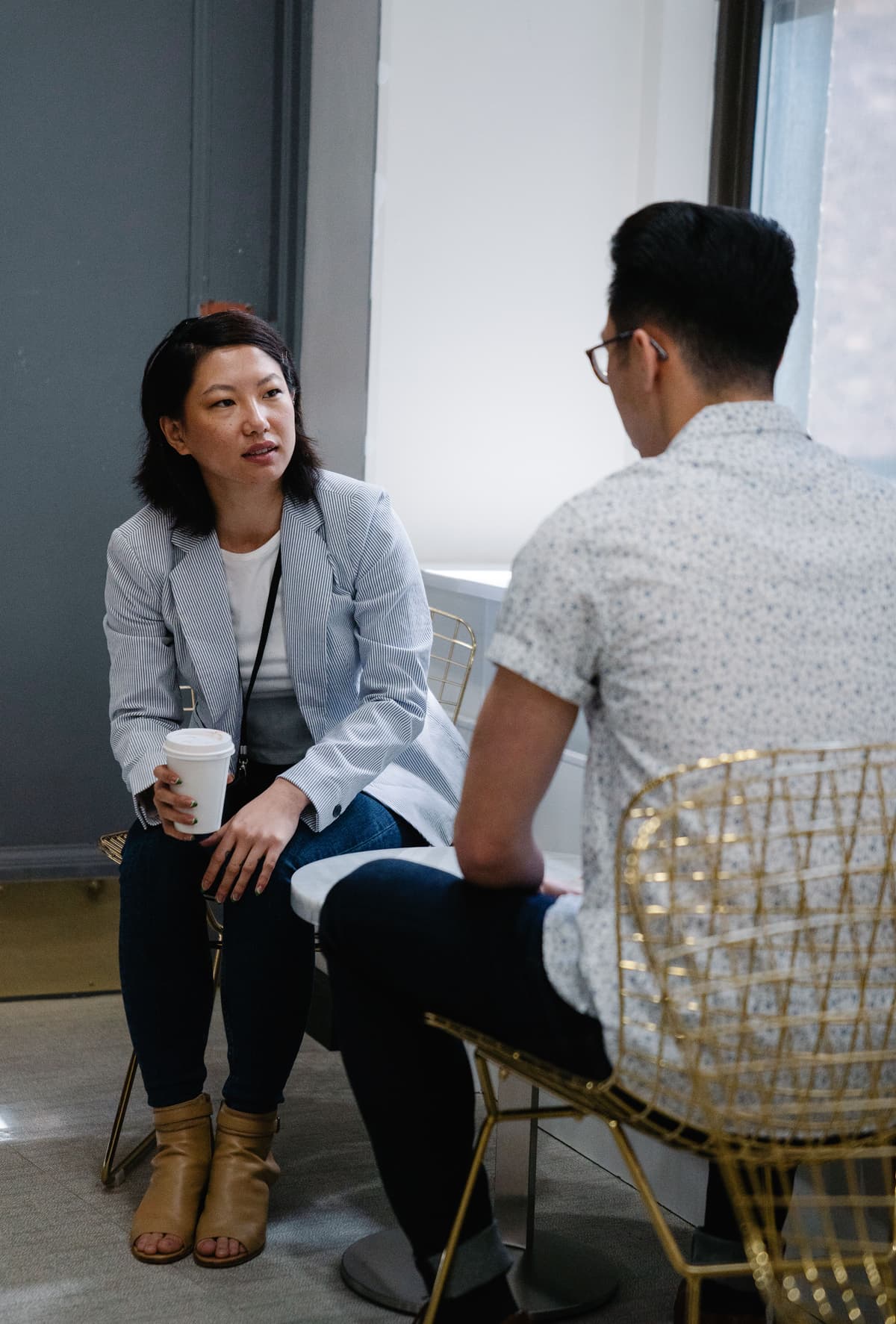 Two people sitting across from each other at a cafe table during a conversation.