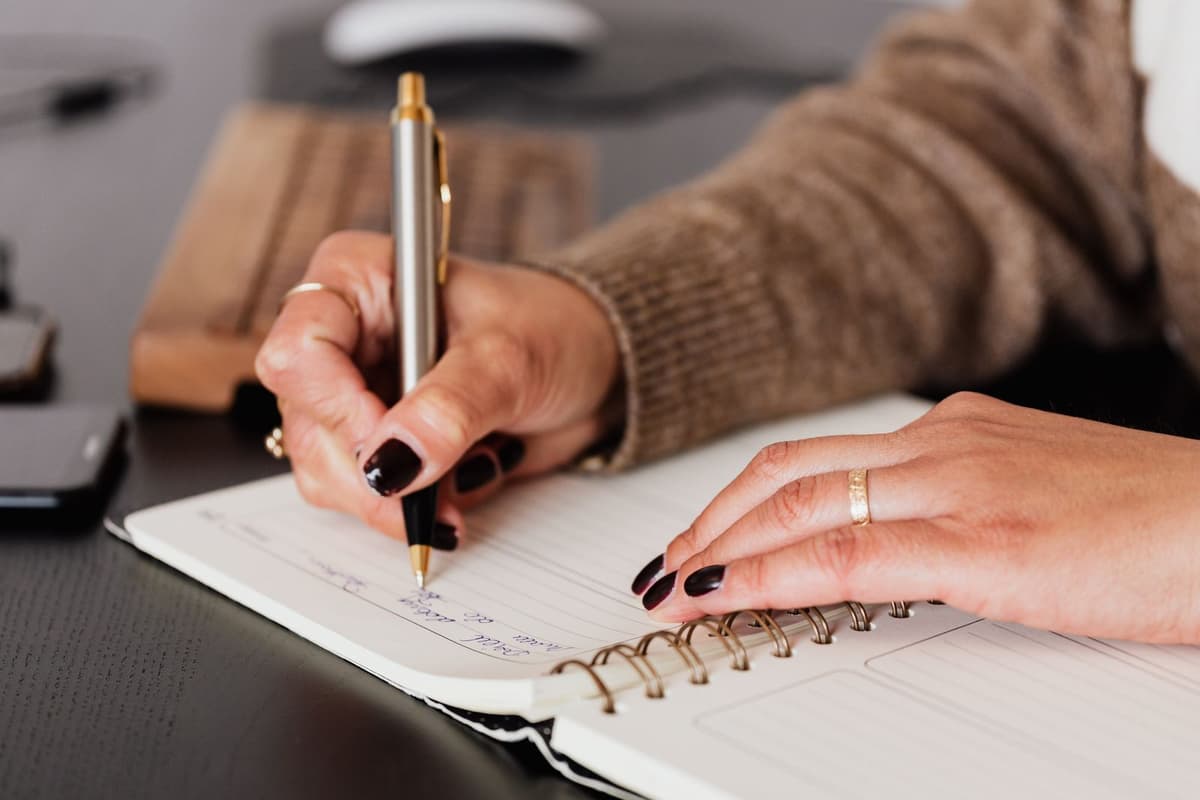 Close-up of a person writing notes in an open diary.