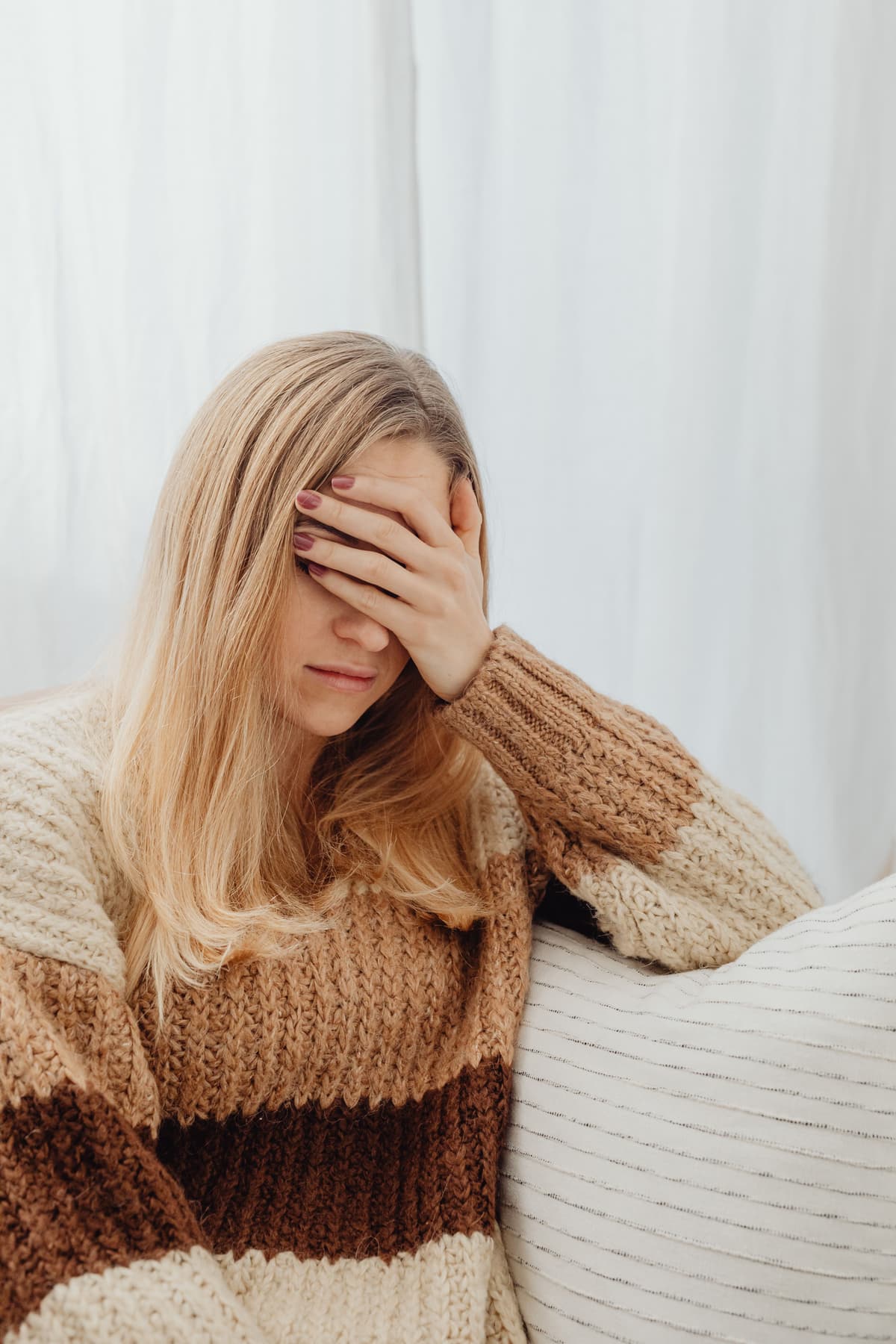 A person sitting with one hand pressed to their forehead.