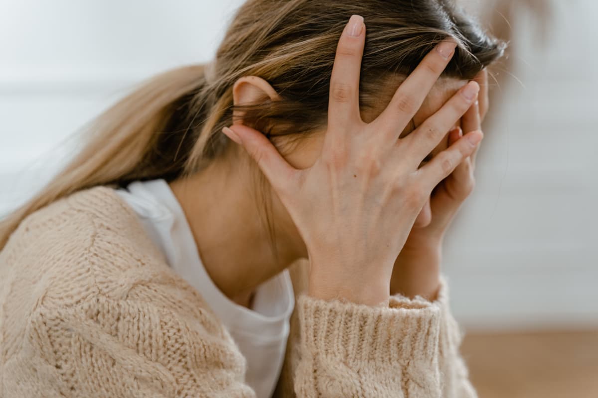 Close-up of a person sitting with their head in their hands.