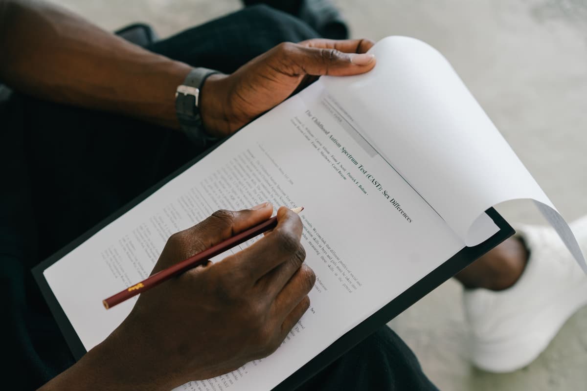 Close-up of someone writing notes on a printed form clipped to a board.