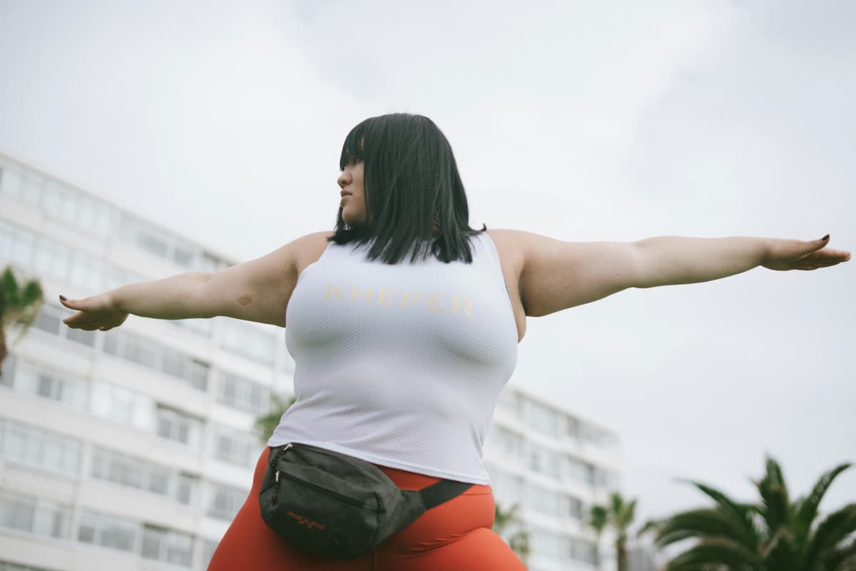 A person standing outdoors with both arms stretched wide.