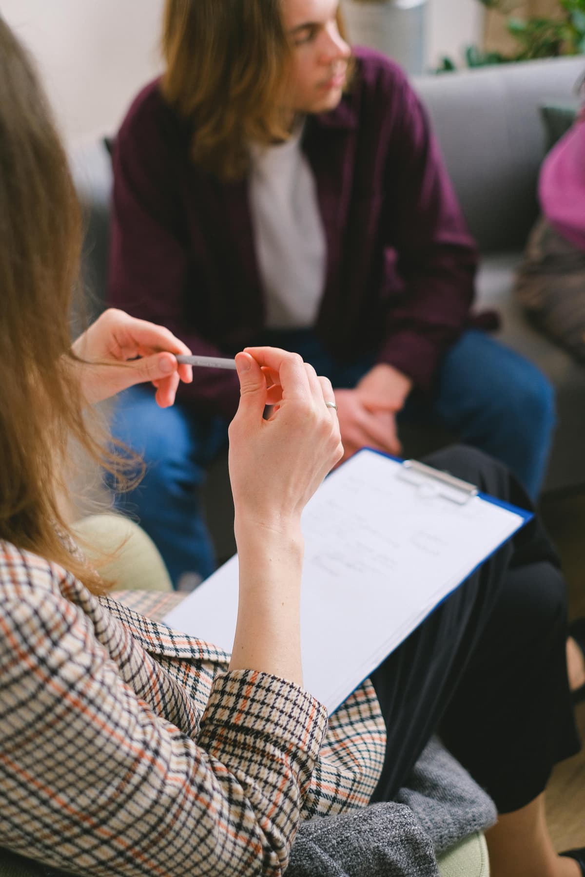 A therapist holding a clipboard while meeting with a couple.