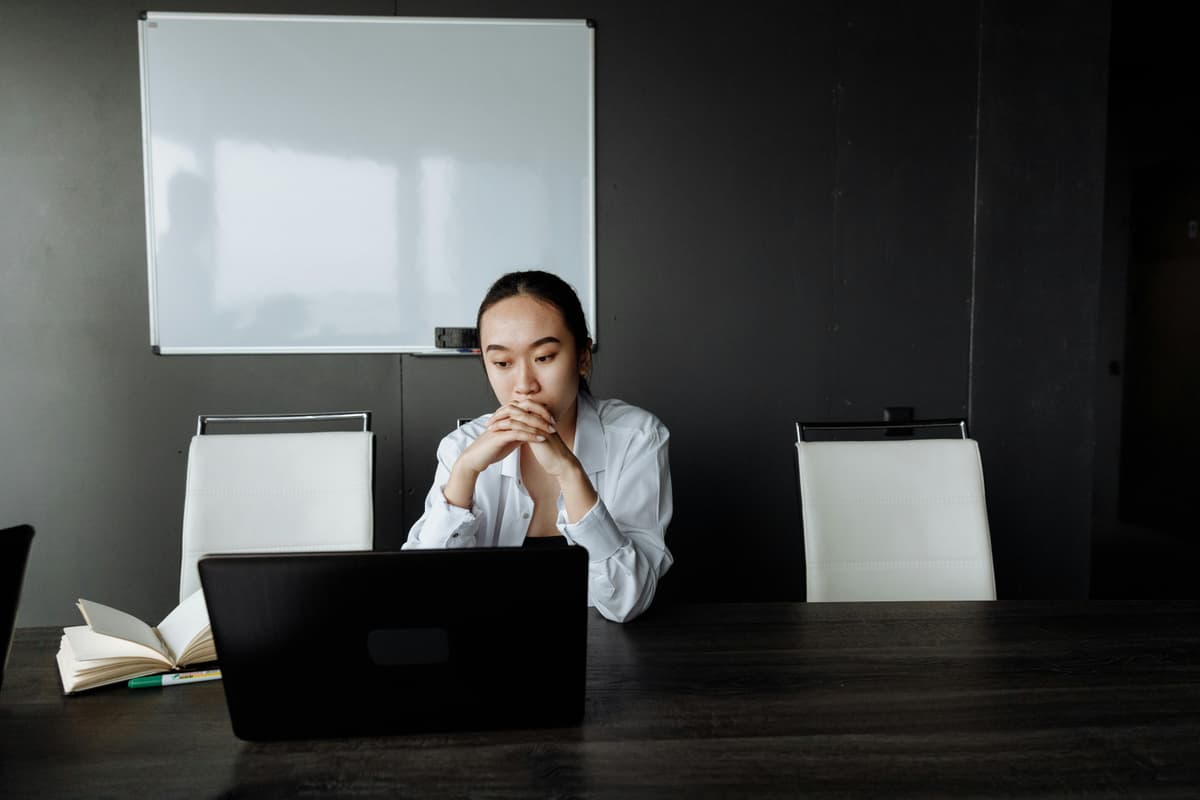 A woman looking at a laptop with a thoughtful expression, suggesting comparison and reflection.