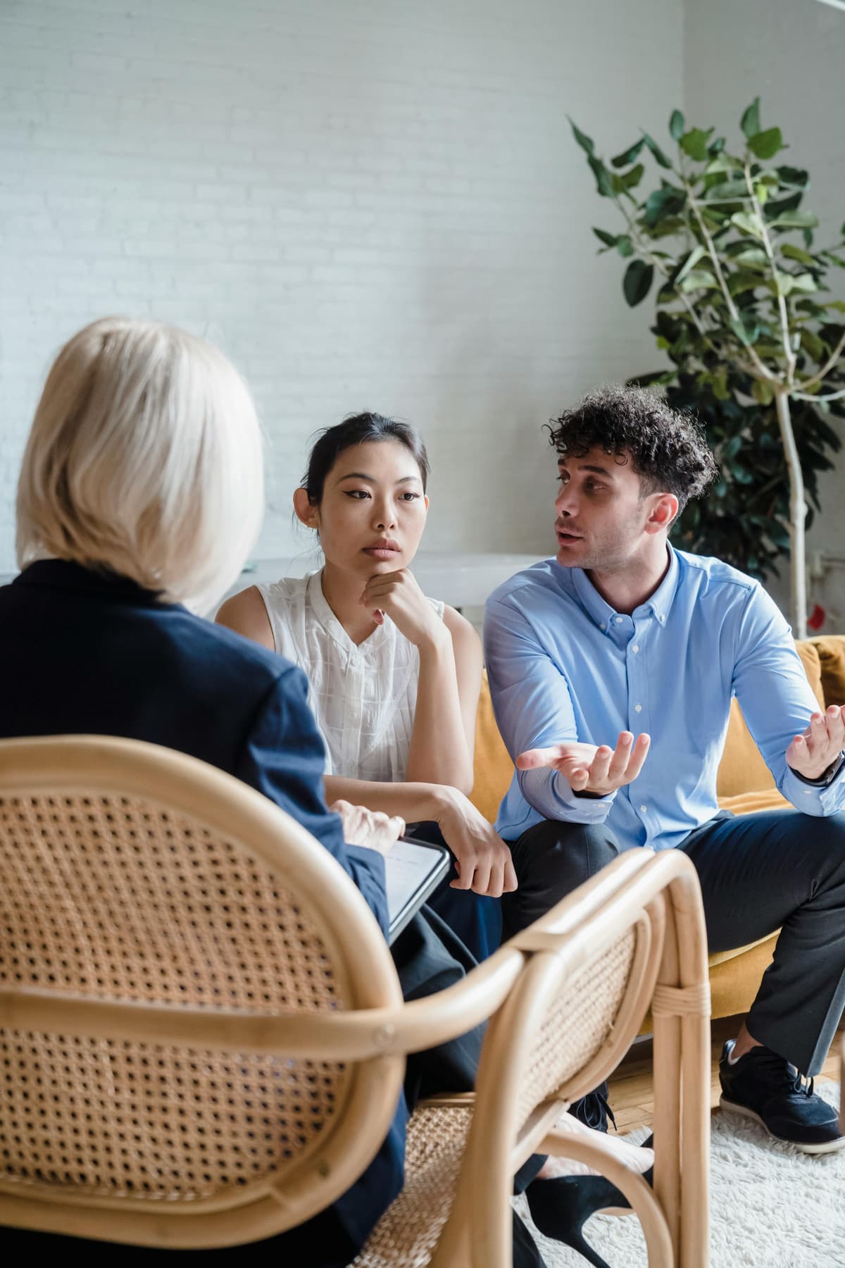 A couple speaking with a therapist in a bright office.
